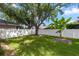 Fenced backyard with lush grass, mature trees, and a brick patio area at 10299 Cypress Knee Cir, Orlando, FL 32825