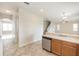 Open kitchen with wood cabinets, stainless steel dishwasher, and views to the living area and staircase at 10299 Cypress Knee Cir, Orlando, FL 32825