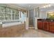 Relaxing bathroom featuring a soaking tub, glass shower, natural light, and tiled floors at 1097 Harmony Ln, Clermont, FL 34711