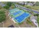 Aerial view of the tennis and basketball courts, beautifully landscaped with mature trees and convenient sidewalks at 1097 Harmony Ln, Clermont, FL 34711