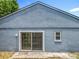Exterior backyard view features sliding glass doors, and minimal landscaping with the house painted blue at 1131 Tyler Lake Cir, Orlando, FL 32839