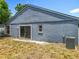 Exterior backyard view features sliding glass doors, and minimal landscaping with the house painted blue at 1131 Tyler Lake Cir, Orlando, FL 32839