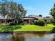 View of the home from across the lake, featuring a screened-in lanai and lush landscaping at 11854 Delfina Ln, Orlando, FL 32827