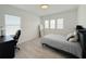 Bright bedroom featuring neutral tones, natural light, sleek gray flooring, and a simple desk and chair setup at 13993 Title Way, Winter Garden, FL 34787