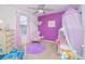 Playful bedroom features a purple accent wall, soft rug, and window with pink curtains at 1785 Red Canyon Dr, Kissimmee, FL 34744