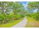 Scenic walking path winding through lush landscaping with trees, tropical foliage, and green grass at 1785 Red Canyon Dr, Kissimmee, FL 34744