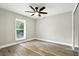 Cozy bedroom featuring wood floors, a modern ceiling fan, and a large window overlooking the yard at 1850 North St, Longwood, FL 32750