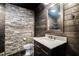 Rustic bathroom features stone accent wall, wood paneling, and vanity with a marble countertop and framed mirror at 1911 Canton St, Orlando, FL 32803