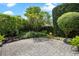 A paved, shady backyard area with rock landscaping and manicured bushes and trees at 2256 Kettle Dr, Orlando, FL 32835