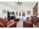 Cozy living room with comfortable leather furniture, a ceiling fan, and sliding glass doors with a pool view at 235 Hidden Springs Cir, Kissimmee, FL 34743