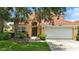 Charming home with a red tile roof, lush landscaping, and an attached two-car garage at 255 Cordova Ave, Davenport, FL 33897
