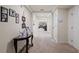 Bright, neutral hallway with carpeted floors, decorative table, art display and white doors at 2613 Breezy Meadow Rd, Apopka, FL 32712