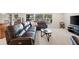 Comfortable living room with a plush leather sofa, large window, and a modern TV setup at 2613 Breezy Meadow Rd, Apopka, FL 32712