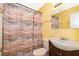 Yellow bathroom featuring a vanity sink, mirror, toilet and bathtub-shower with patterned shower curtain at 2918 E Central Blvd, Orlando, FL 32803
