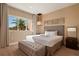Bright bedroom featuring a king bed, tufted ottoman, and a large window with a palm tree view at 3056 Rockefeller Way, Kissimmee, FL 34747
