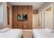 Well-lit bedroom featuring two beds, wood accent wall, TV, and a door leading to another room at 3056 Rockefeller Way, Kissimmee, FL 34747