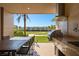 Outdoor kitchen featuring a built-in grill, a dining table, and views of the lush surrounding landscape at 3056 Rockefeller Way, Kissimmee, FL 34747