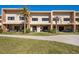 Rear view of condo building featuring patios with outdoor seating and manicured lawn at 3056 Rockefeller Way, Kissimmee, FL 34747