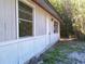 Side view of the home featuring two windows and a white front door with bamboo in the background at 31429 Anna St, Deland, FL 32720