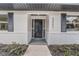 Close-up of the front door, featuring white brick accents, black shutters, and decorative plants at 5882 Marlberry Dr, Orlando, FL 32819