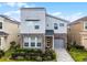 Modern two-story home featuring a stone facade, gray siding, a paved driveway, and manicured landscaping at 8913 Coconut Breeze Dr, Kissimmee, FL 34747