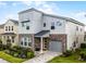 Contemporary two-story home with stone accents, gray siding, well-maintained landscaping, and an attached one-car garage at 8913 Coconut Breeze Dr, Kissimmee, FL 34747