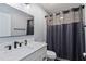 Bathroom with sleek black fixtures, a white vanity, and a tiled shower with a dark shower curtain at 9067 Stonebury Way, Orlando, FL 32832