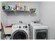 Functional laundry room with a washer, dryer, and storage shelving at 9067 Stonebury Way, Orlando, FL 32832