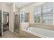 Well-lit bathroom with a separate glass-enclosed shower and soaking tub under a large window at 10117 Sweetleaf St, Orlando, FL 32827