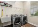 Well-equipped laundry room with modern washer and dryer, sink, and storage shelves at 10117 Sweetleaf St, Orlando, FL 32827