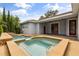 Exterior view of a pool and hot tub with a covered porch and red doors on the rear of the house at 10117 Sweetleaf St, Orlando, FL 32827
