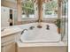 Corner tub and windows featuring decorative accents, tile, and a view of the walk-in shower at 1041 Cherry Valley Way, Orlando, FL 32828