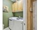 Modern laundry room with white front-loading washer and dryer and wood cabinets above at 1041 Cherry Valley Way, Orlando, FL 32828