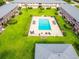 Aerial view of a bright blue community pool with ample seating surrounded by green lawn and buildings at 1100 E Caroline St # 204, Tavares, FL 32778