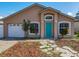 Charming single-story home with a well-maintained lawn, a teal front door and an attached garage at 1115 Naples Dr, Orlando, FL 32804