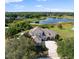 Stunning aerial view of a home with a large lake, lush greenery, and a spacious driveway at 13025 Lake Roper Ct, Windermere, FL 34786
