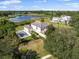 An aerial view of a house with a sport court and a lake, set against lush, green landscaping and trees at 13025 Lake Roper Ct, Windermere, FL 34786