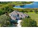 Stunning aerial view of a grand home with a tile roof, mature trees, and a tranquil lake backdrop at 13025 Lake Roper Ct, Windermere, FL 34786
