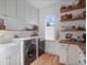 Bright laundry room features white cabinets, butcher block counters, open shelving, and modern washer/dryer at 13025 Lake Roper Ct, Windermere, FL 34786