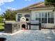 Outdoor kitchen with a built-in grill, pizza oven, and concrete pavers set against a backyard with green grass at 13025 Lake Roper Ct, Windermere, FL 34786