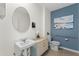 Small bathroom features a vanity, a sink with chrome fixtures, an oval mirror, and a toilet set against a blue accent wall at 1419 Birwood St, Deltona, FL 32725