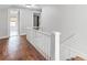 Upstairs hallway with bright white walls and natural wood floors leading to bedrooms at 25 E Pinecrest Ave, Eustis, FL 32726