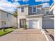 Two-story townhouse showcasing one car garage, neutral colors, palm tree, and a brick driveway at 2596 Penguin Blvd, Davenport, FL 33837