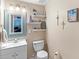 Cozy bathroom with a light blue framed mirror, decorative shelves, and a standard toilet at 3055 Ashland N Ln, Kissimmee, FL 34741