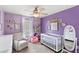 Bedroom featuring purple walls, chair, ceiling fan, and crib at 3055 Ashland N Ln, Kissimmee, FL 34741