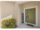 Welcoming entrance with an olive-green door, 'Welcome' sign, and verdant landscaping at 3055 Ashland N Ln, Kissimmee, FL 34741