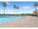 Community pool with lounge chairs, a brick patio, and tropical palm trees in the background at 3055 Ashland N Ln, Kissimmee, FL 34741