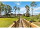 A wooden walkway extends to a fenced backyard with lush grass and trees, leading to an inviting residential property at 3404 Shallow Cove Ln, Clermont, FL 34711