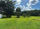 Lush green backyard with a variety of trees, bathed in sunlight and open sky at 431 Eagle Dr, Poinciana, FL 34759