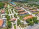 Aerial view of a community with red-tiled roofs, lush landscaping, and a lake on a sunny day at 4558 Baleno Ln, Kissimmee, FL 34746